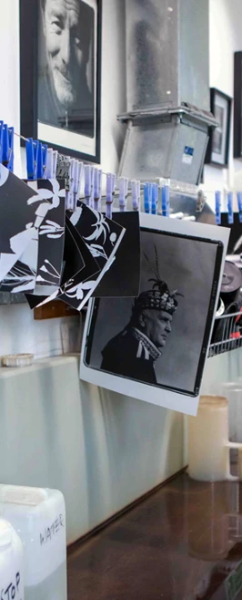 Black and white prints hanging to dry in a darkroom with a photography-themed gallery wall. Black and white prints hanging to dry in a darkroom with a photography-themed gallery wall.